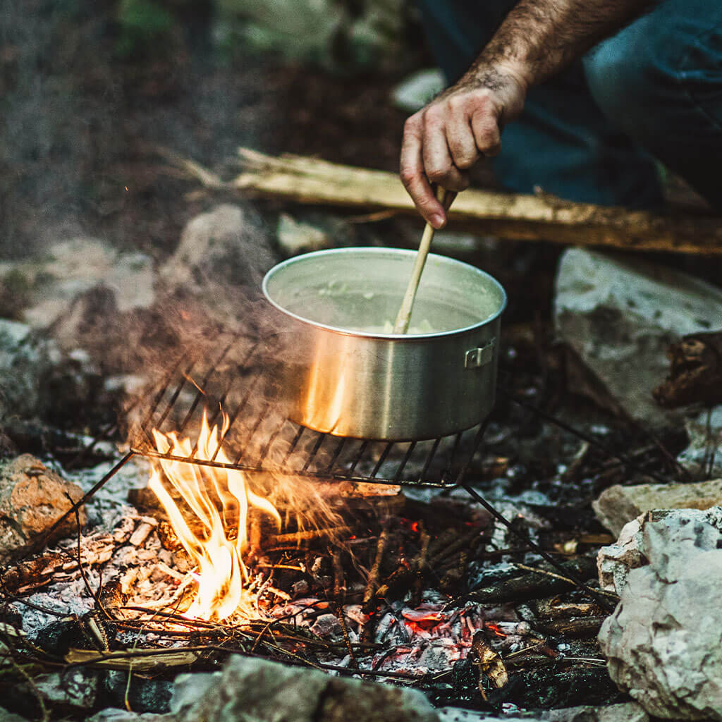 Boiling water over campfire.