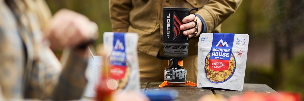 Close-up of two campers preparing Mountain House meal pouches.