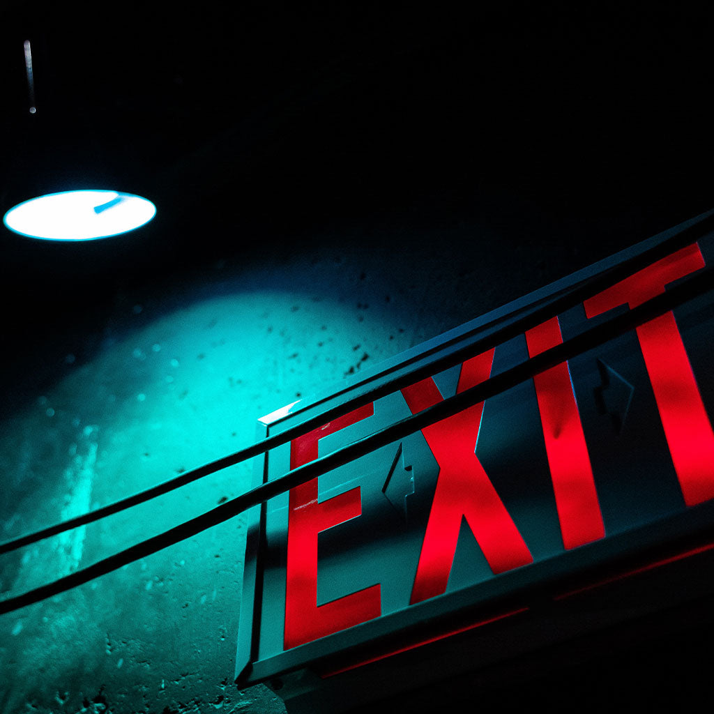 exit sign on wall with light shining down on it
