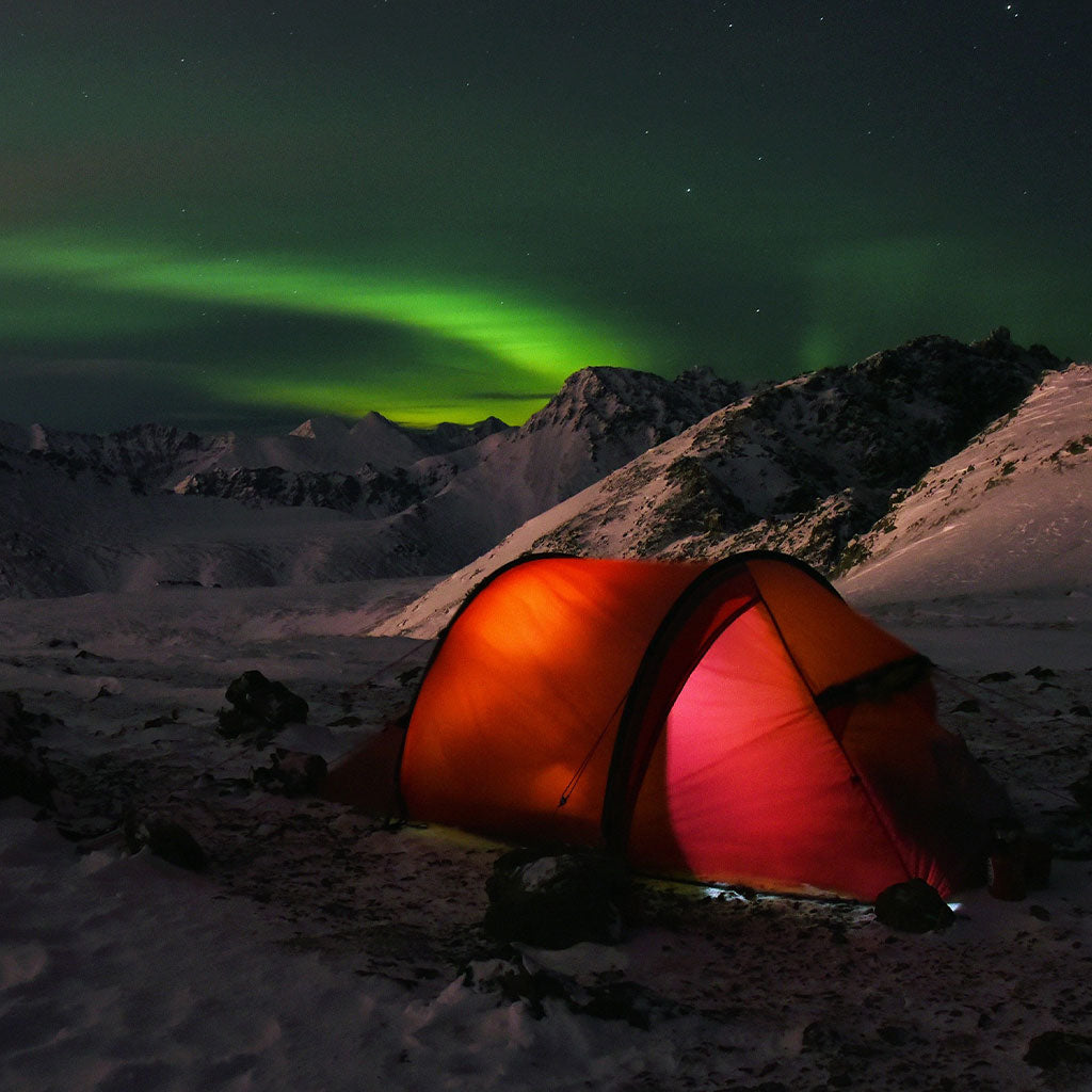 glowing red tent with the aurora in the background