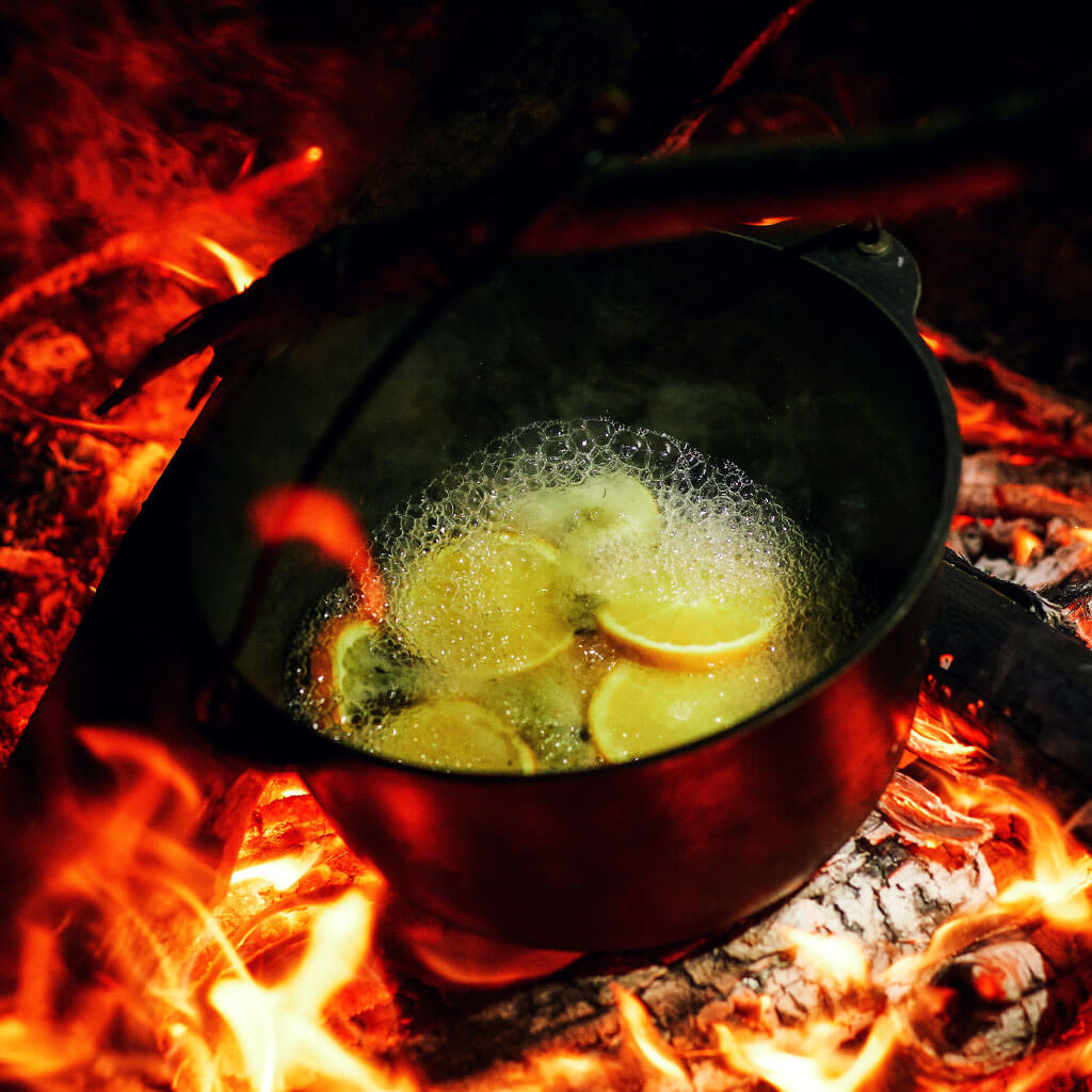 slices of fruit in pot being cooked over campfire