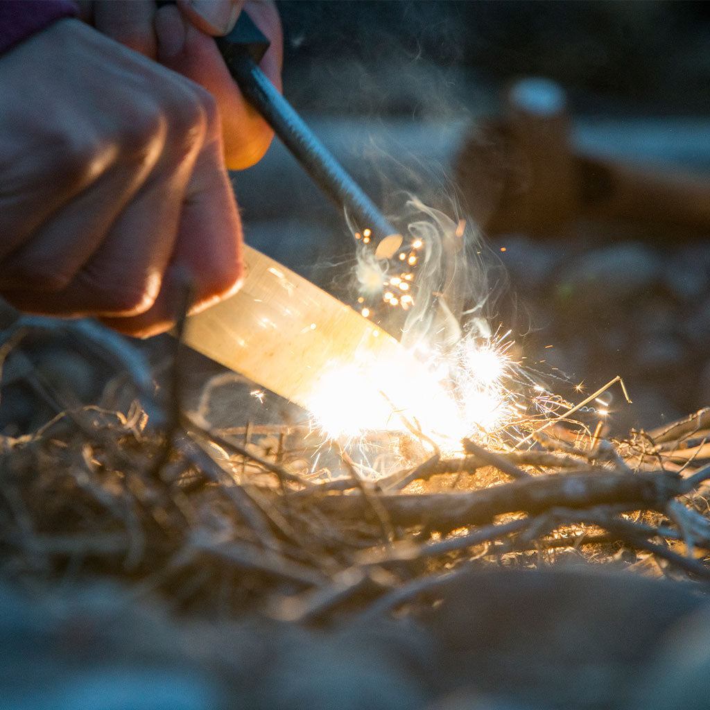 person starting fire with flint and steel