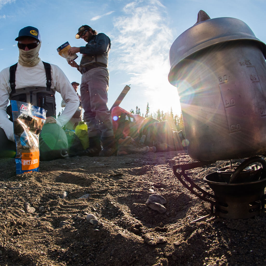two guys looking at mountain house pouches with camp stove in forefront