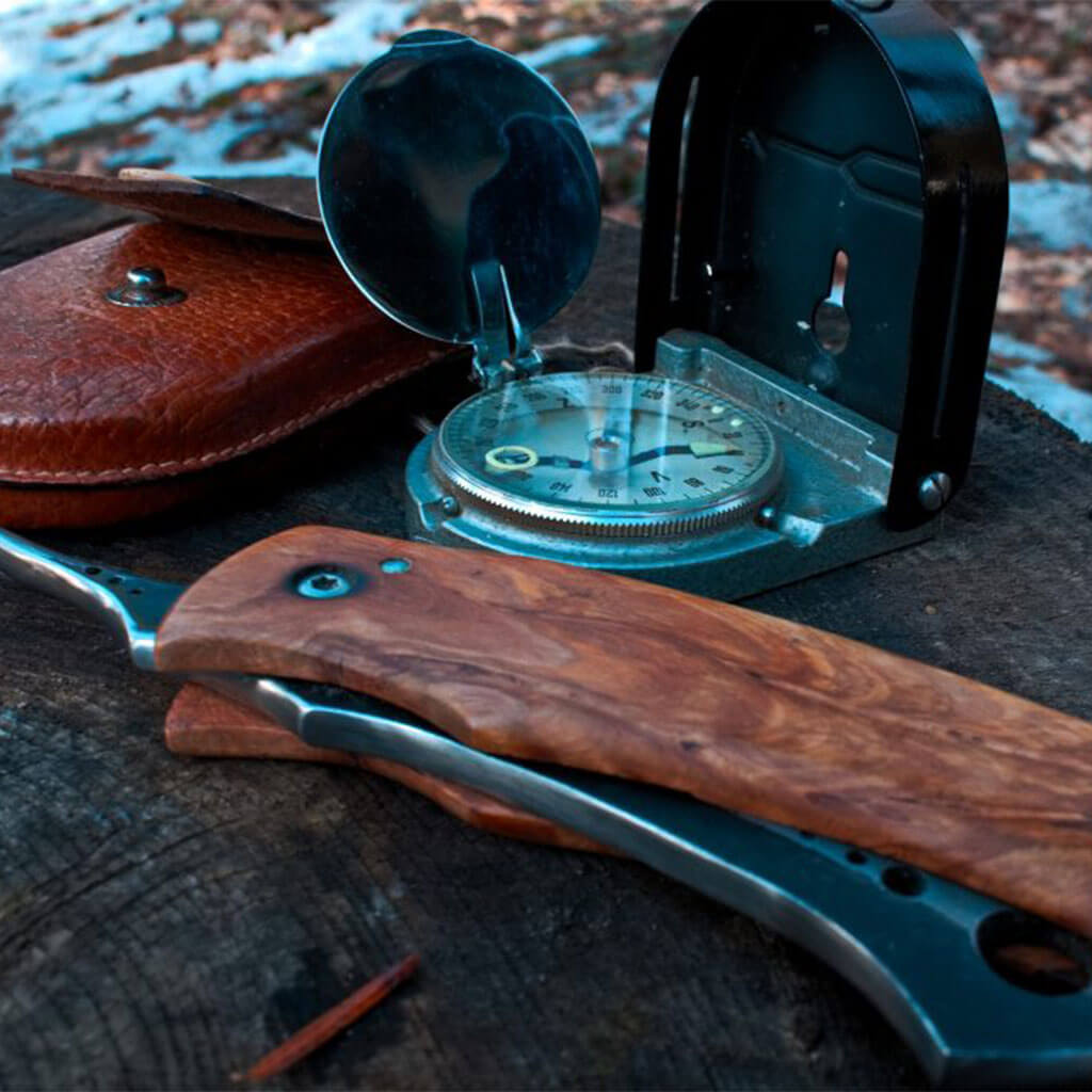 winter survival knife and compass on stump