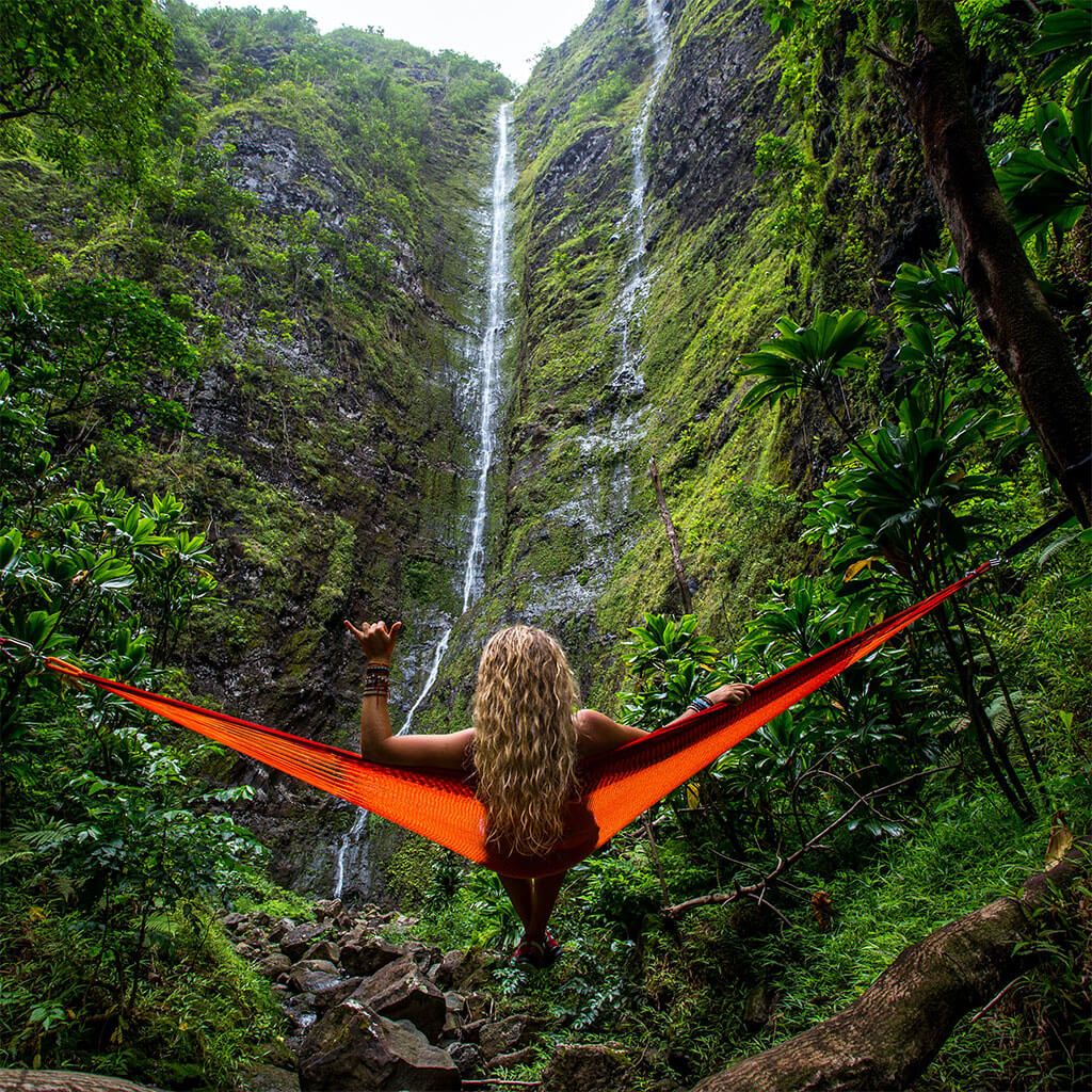 girl sitting in hammock looking at waterfall