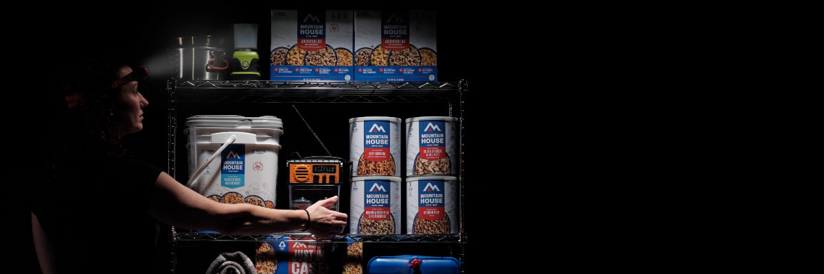 Prepper reviewing 72-hour emergency supplies by flashlight in a dark setting.