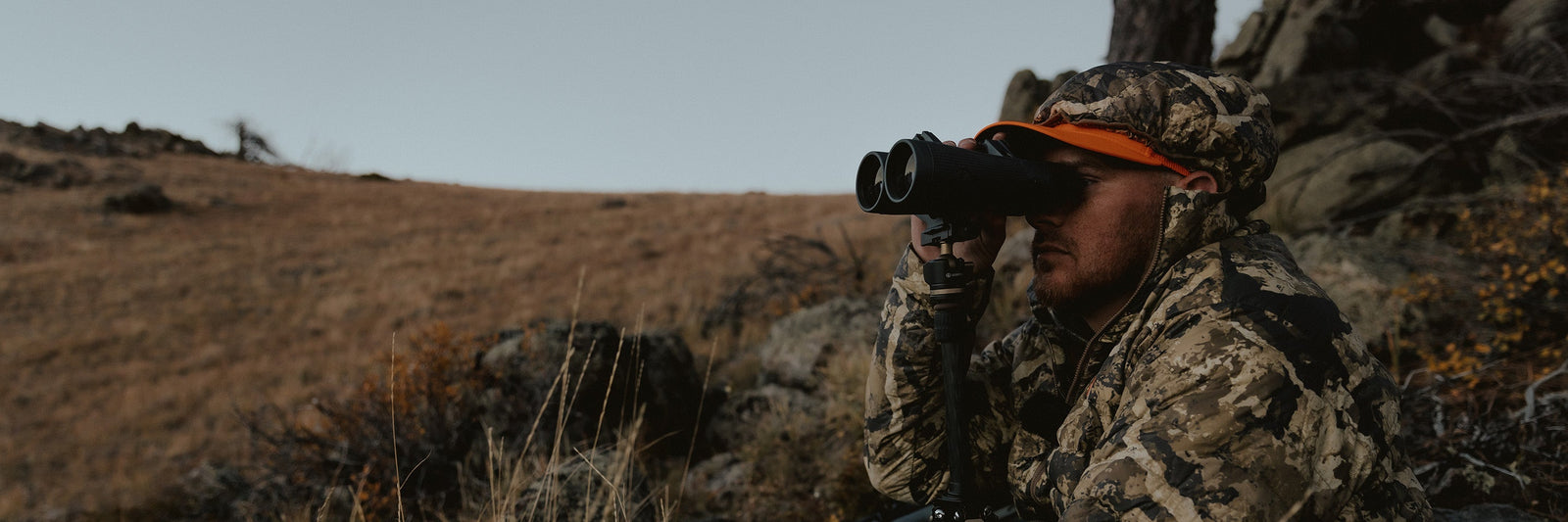 Guy in camouflage glassing field through a pair of Leupold binoculars