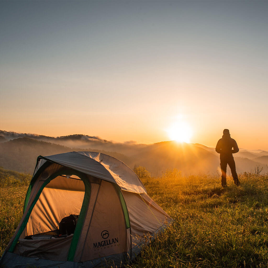 silhouette of person standing next to camping tent