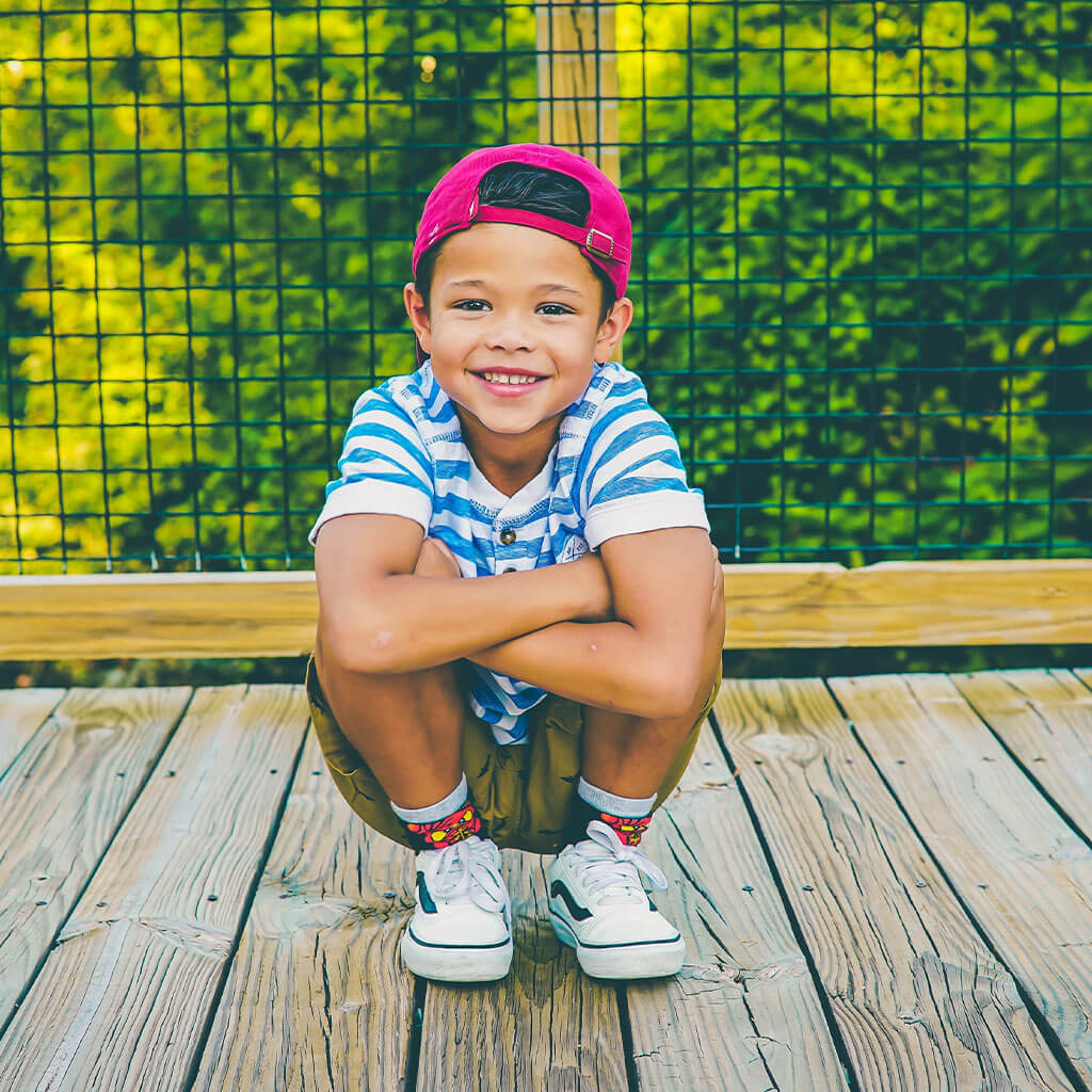 young boy on wooden bridge by railing