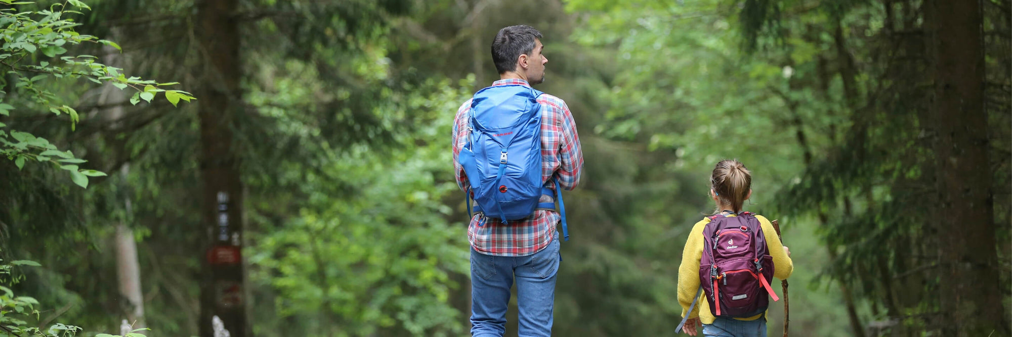 Father and daughter walking in forest with their bug out bags.