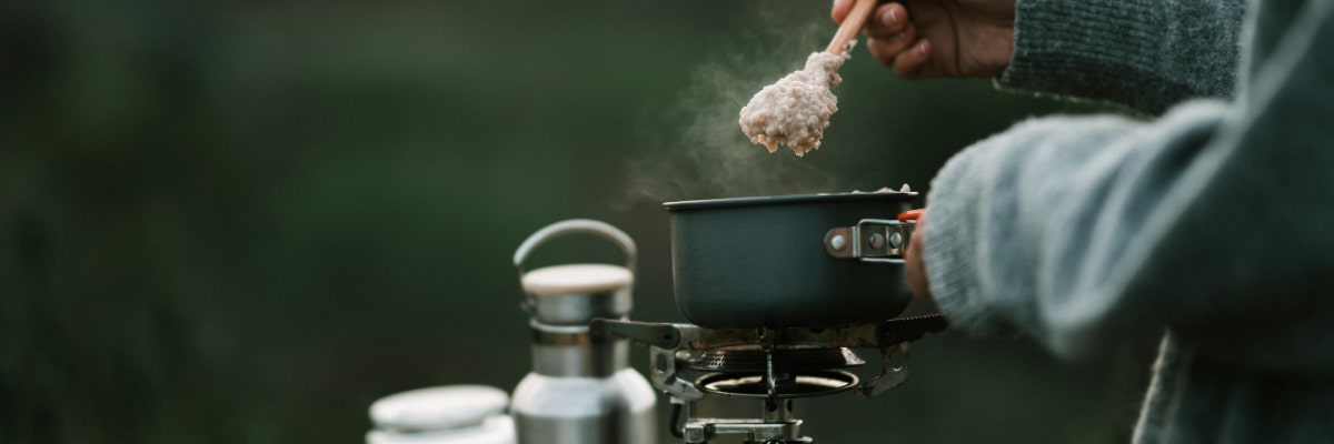 Camper preparing oatmeal breakfast at campsite.