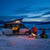 people standing around campfire during winter with camper van in background
