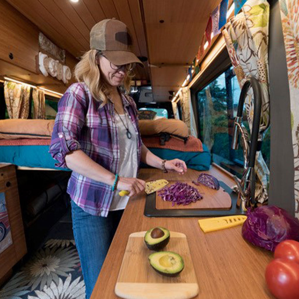 Kelli Martinelli cutting vegetables in a camper van kitchen