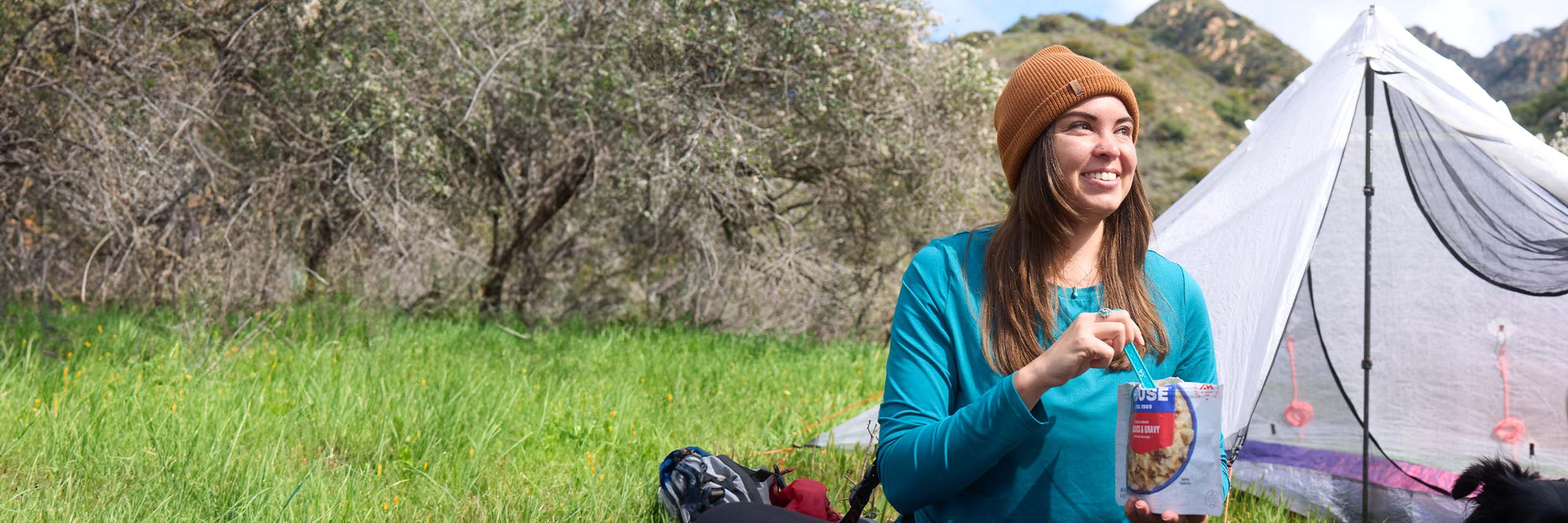 Woman enjoying a high-protein camping meal.