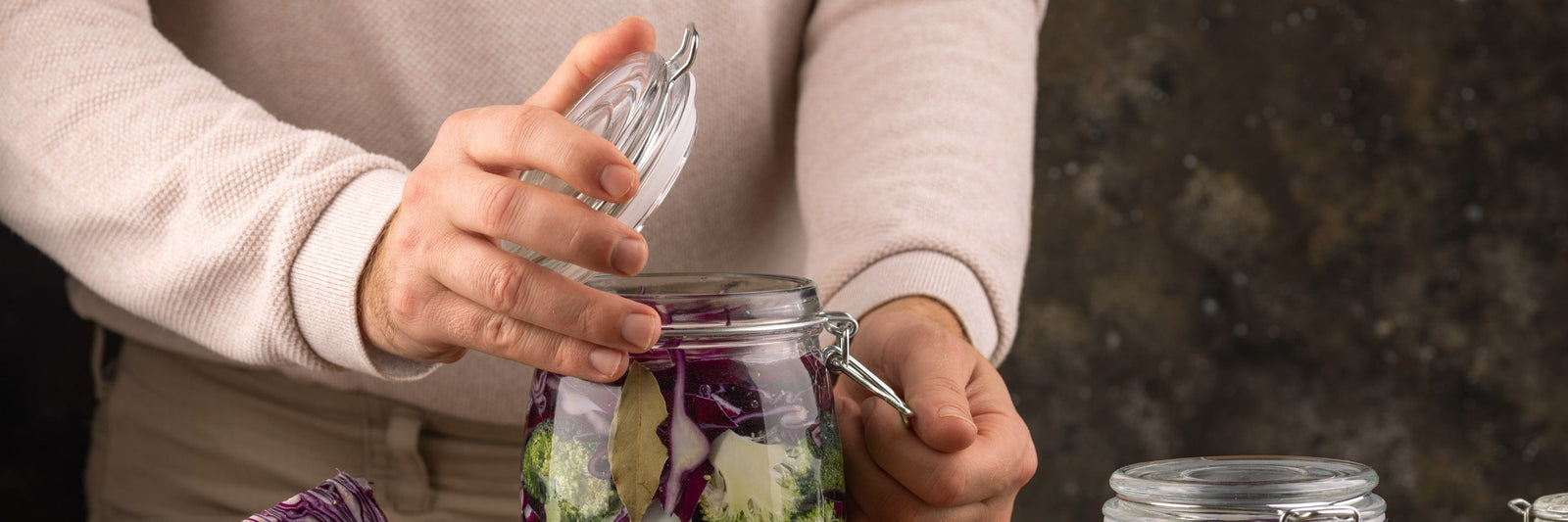 Close up of hands preserving vegetables in mason jars.