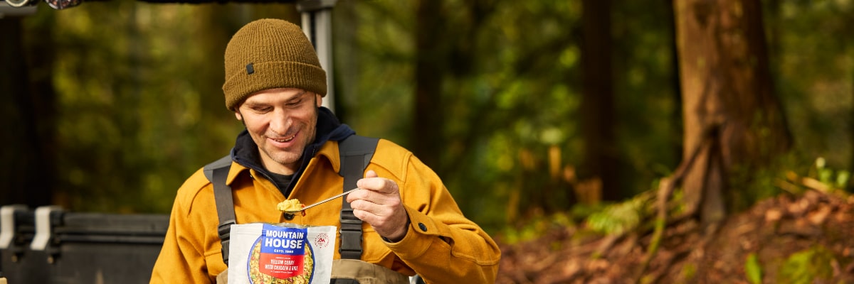 Close-up of a fisherman eating from a Mountain House freeze-dried food pouch.