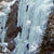 People ice climbing a large ice wall.