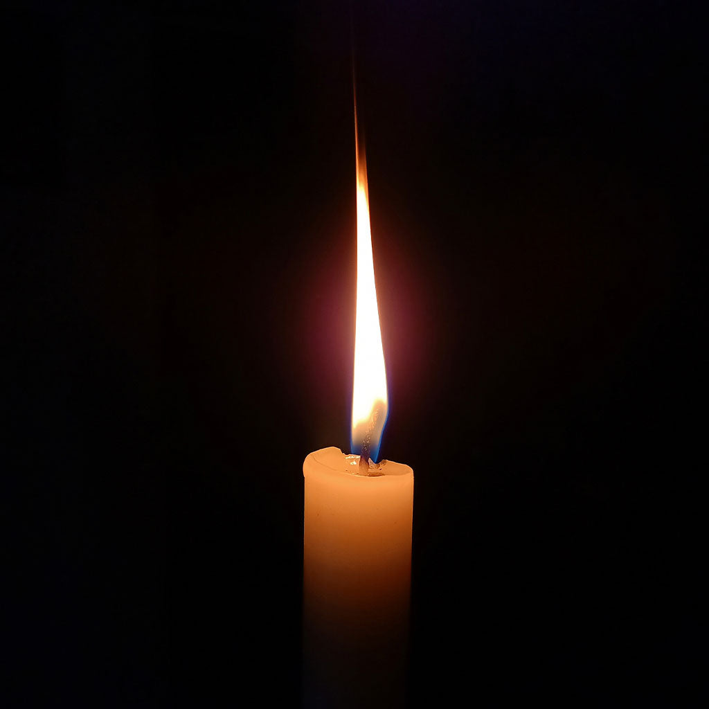 Close-up of a lit candle providing light during a long-term power outage.