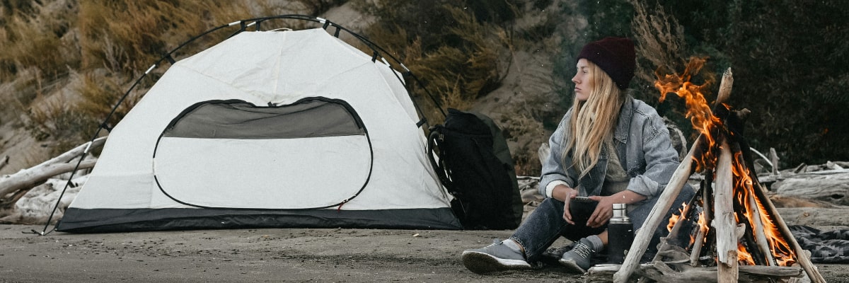 Young woman setting up a minimalist campsite with lightweight gear and a small tent.