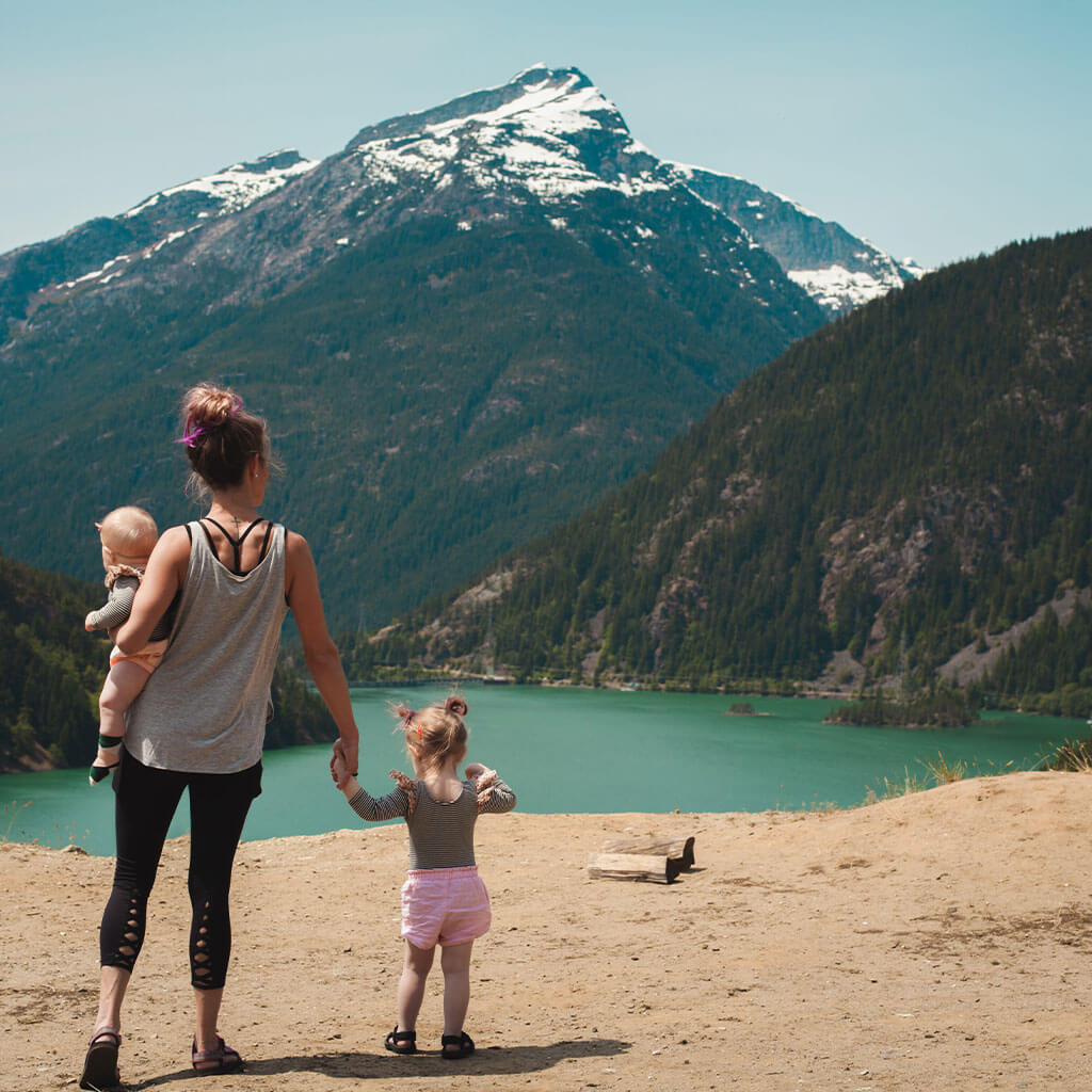 mom and two children overlooking water and mountain peak