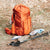 orange rei backpack and trekking poles on ground