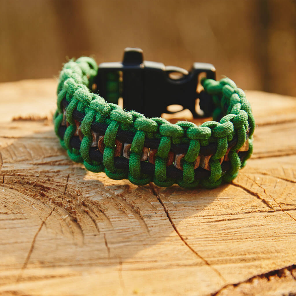Green paracord bracelet on stump.