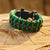 Green paracord bracelet on stump.