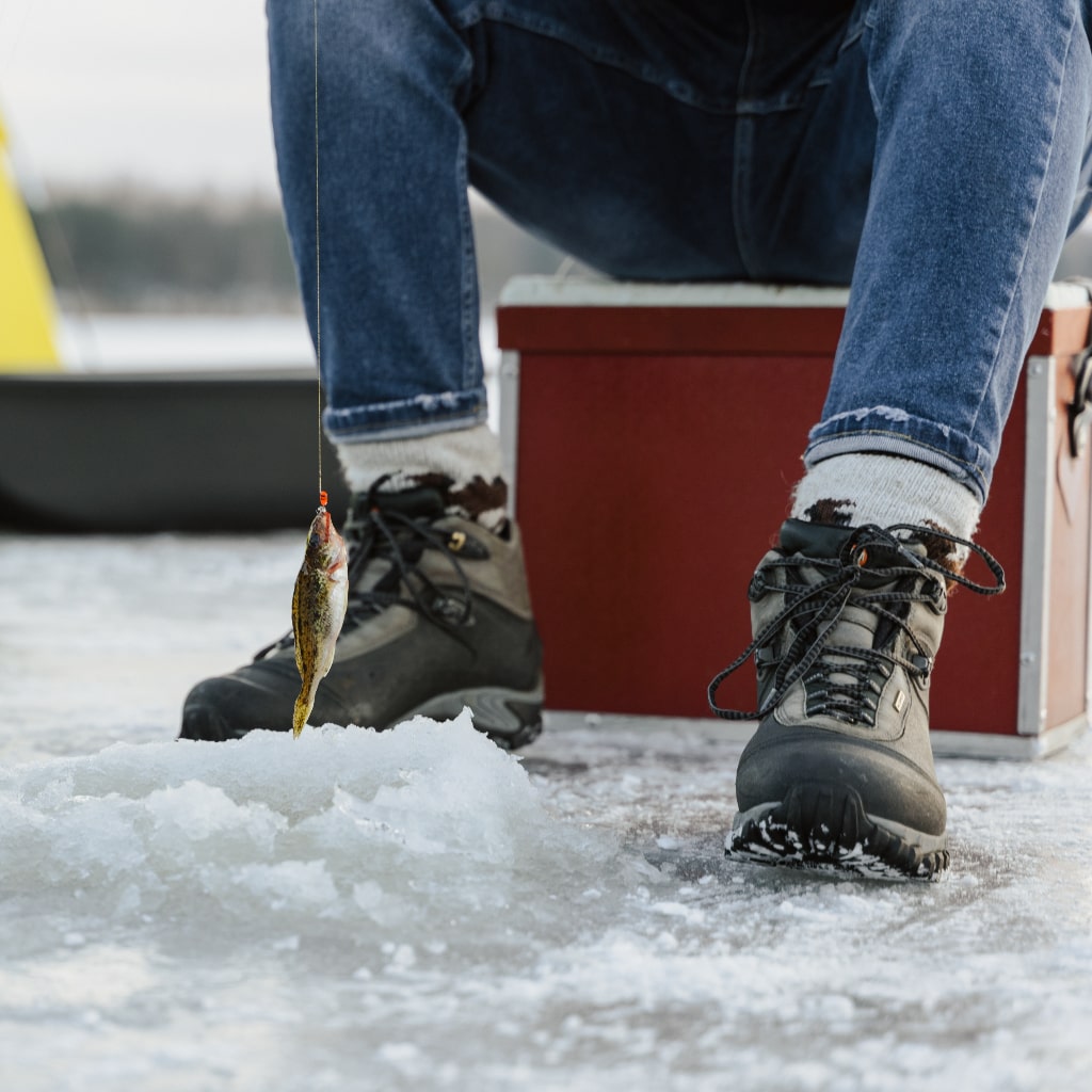 Lower body shot of someone ice fishing.