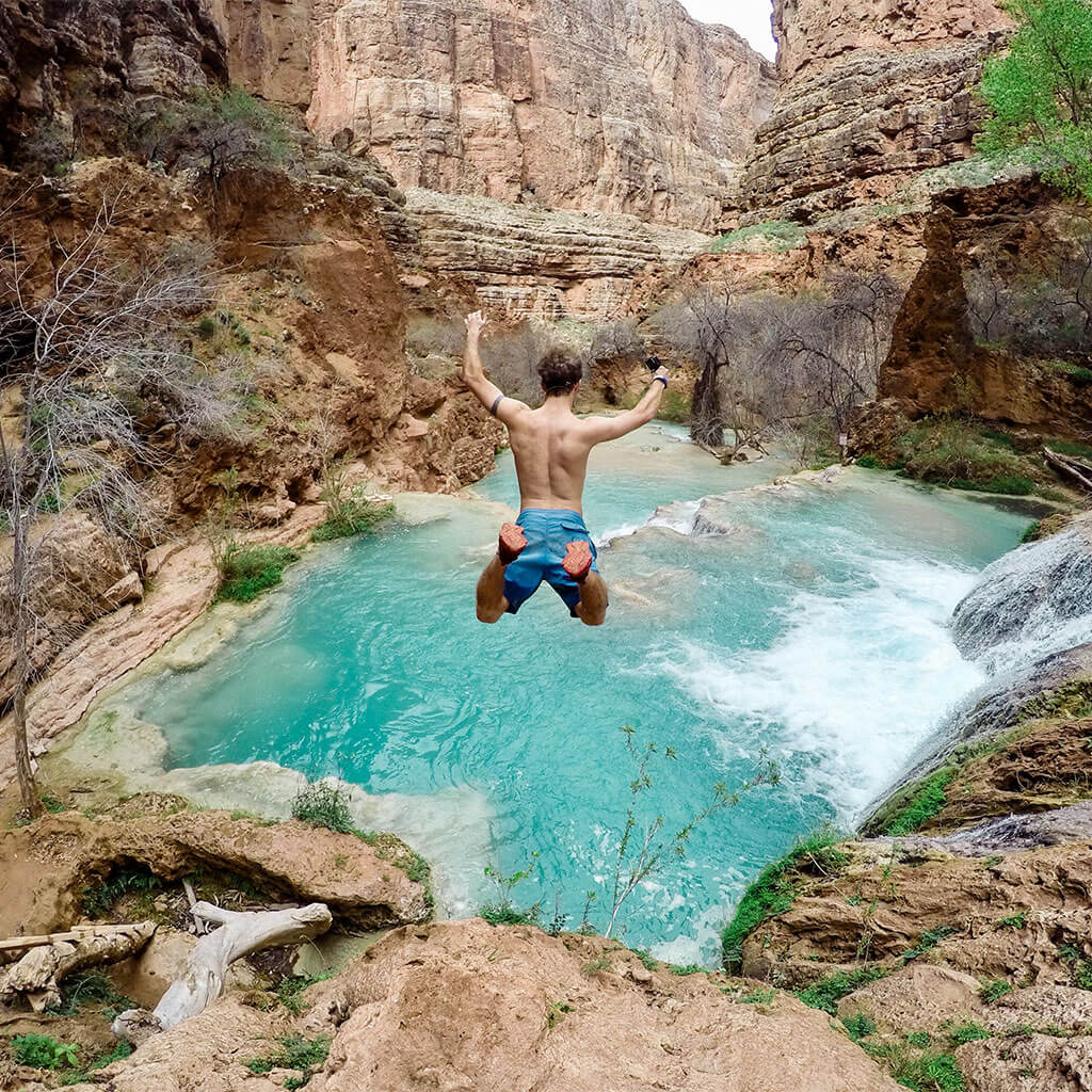 man cliff jumping into blue water