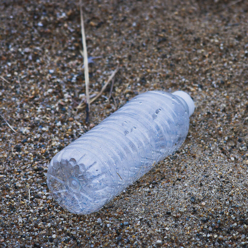 plastic water bottle laying on its side in sand