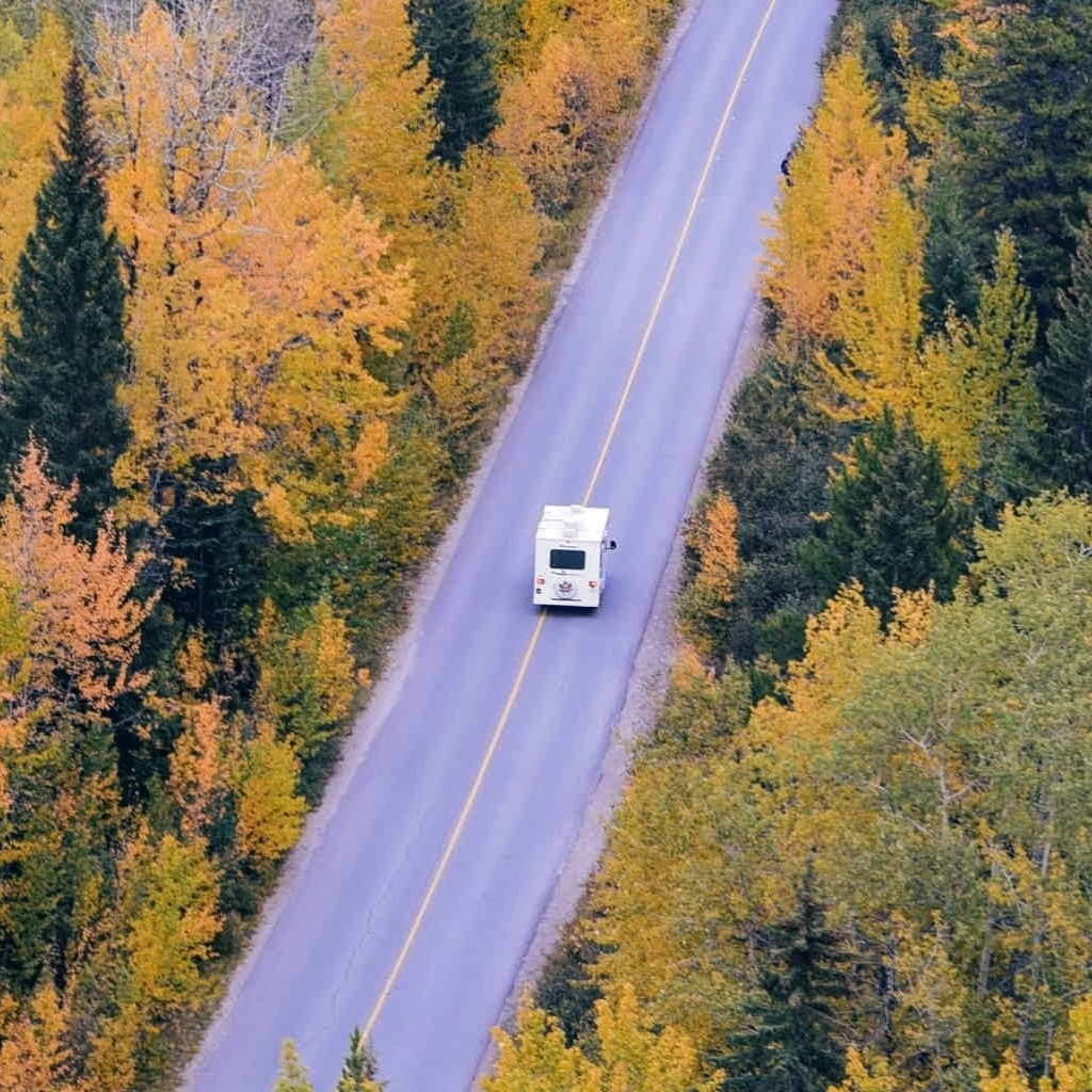 RV driving through forest in the fall.