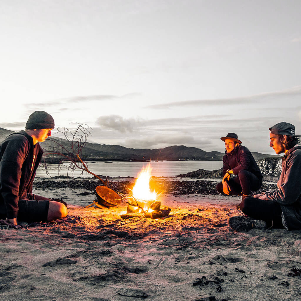 three guys sitting around campfire