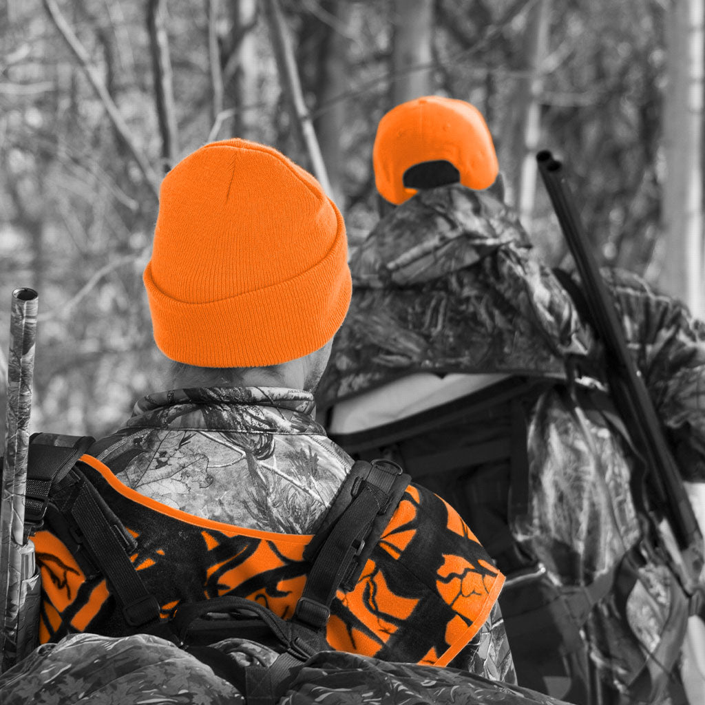 two hunters walking through woods wearing blaze orange