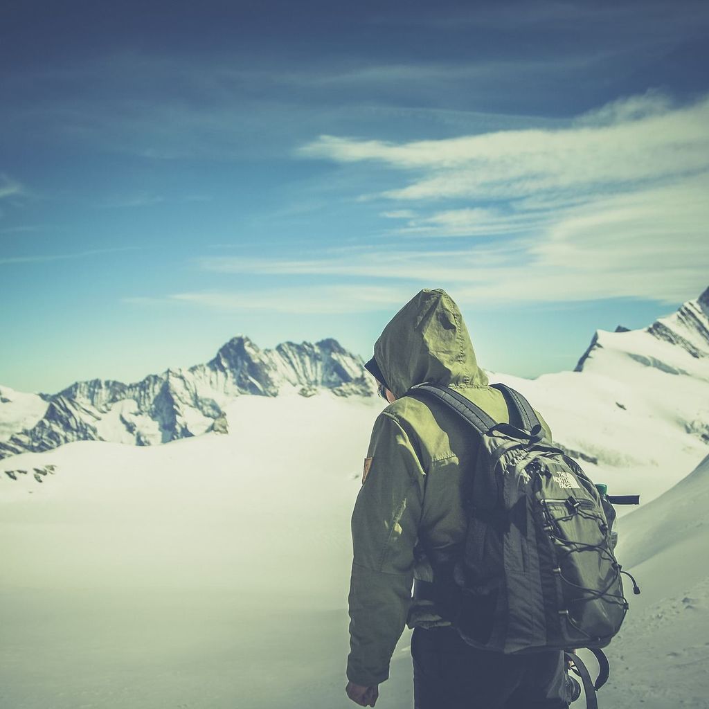 Winter backpacker on snowy mountain slope summit.