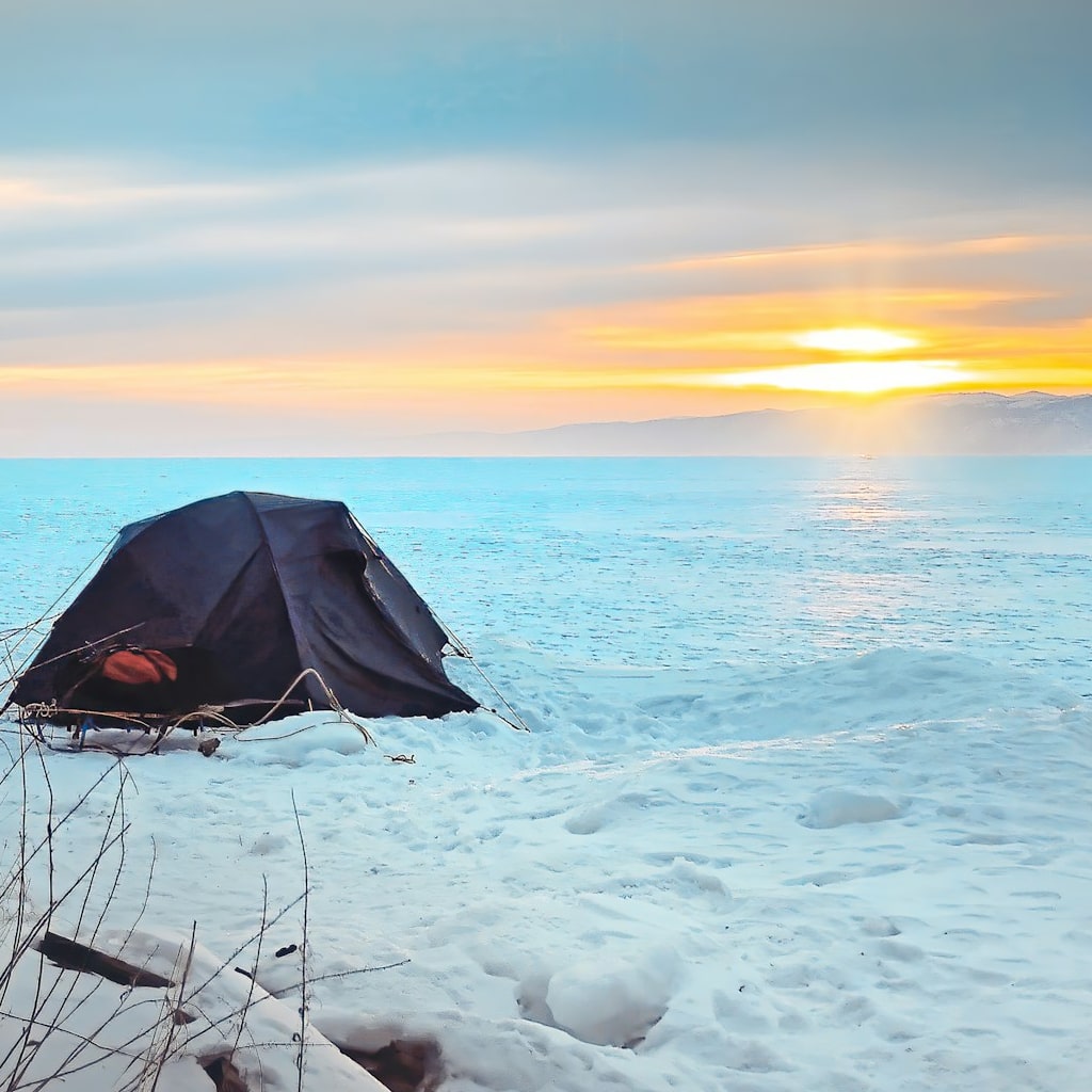 Winter camping tent next to an icy lake.