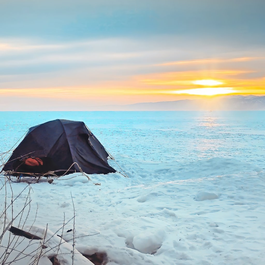 Winter camping tent next to an icy lake.