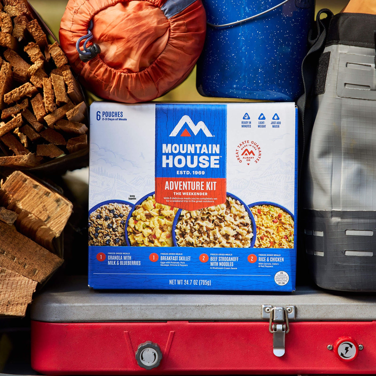 Mountain House Adventure Weekender Kit packed in trunk with other camping supplies like a sleeping bag, firewood, and more.