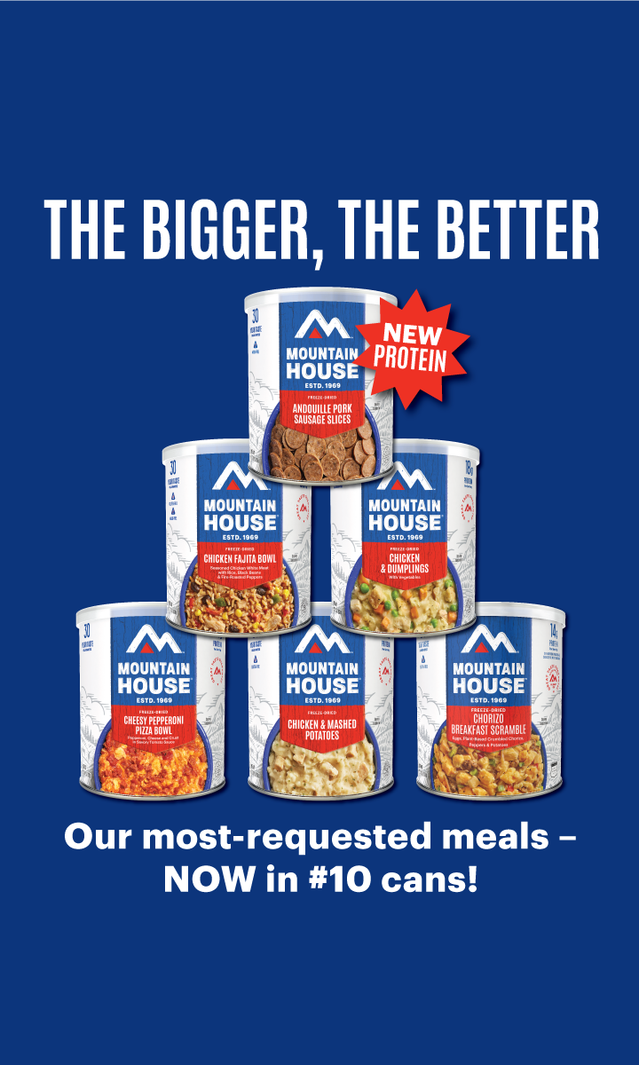 Six Mountain House #10 cans stacked in a pyramid over a blue background. Text: "The Bigger, The Better. Our most-requested meals — NOW in #10 Cans." A starburst near the Andouille Pork Sausage Slices can says "New Protein."