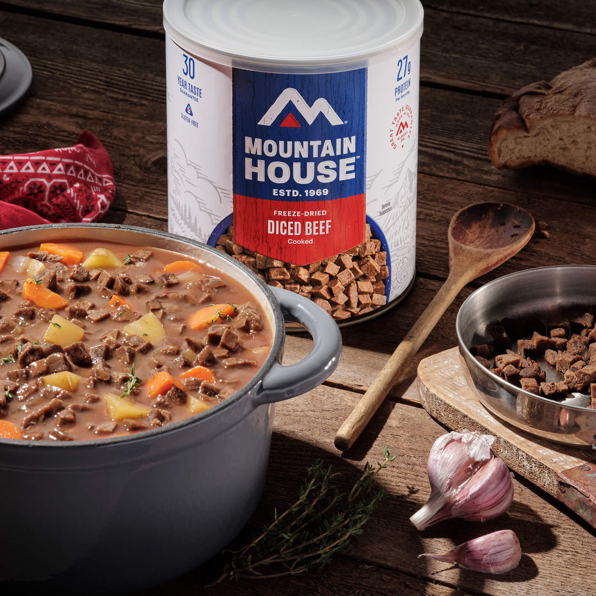 Mountain House freeze-dried diced beef #10 Can with a pot of stew on a wooden table.