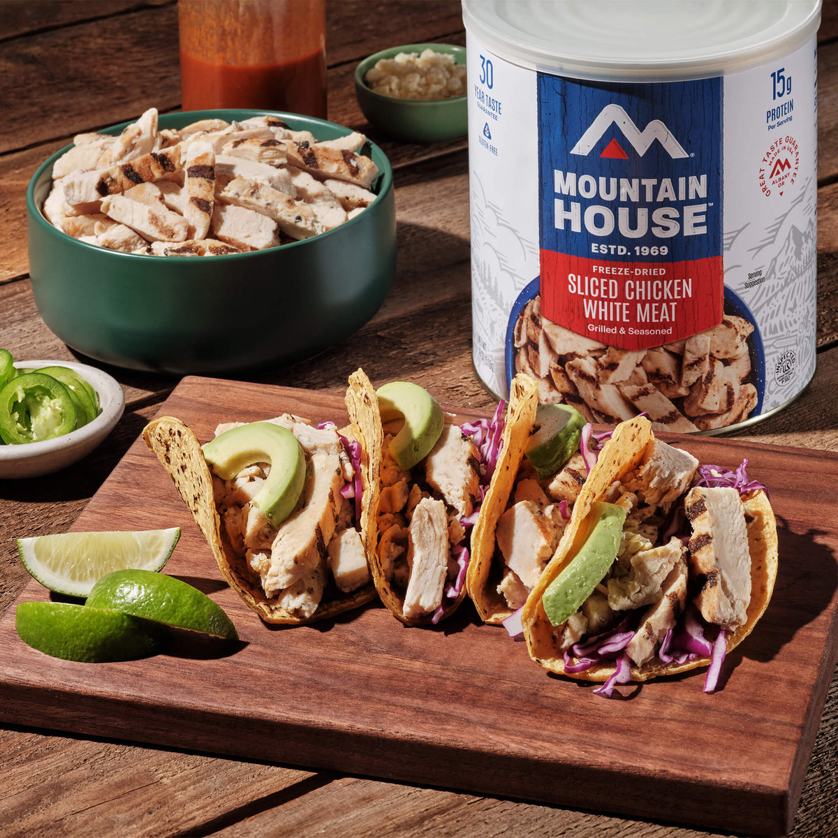 Mountain House Grilled Sliced Chicken #10 Can sitting on a countertop next to chicken tacos and the other ingredients used to make them.