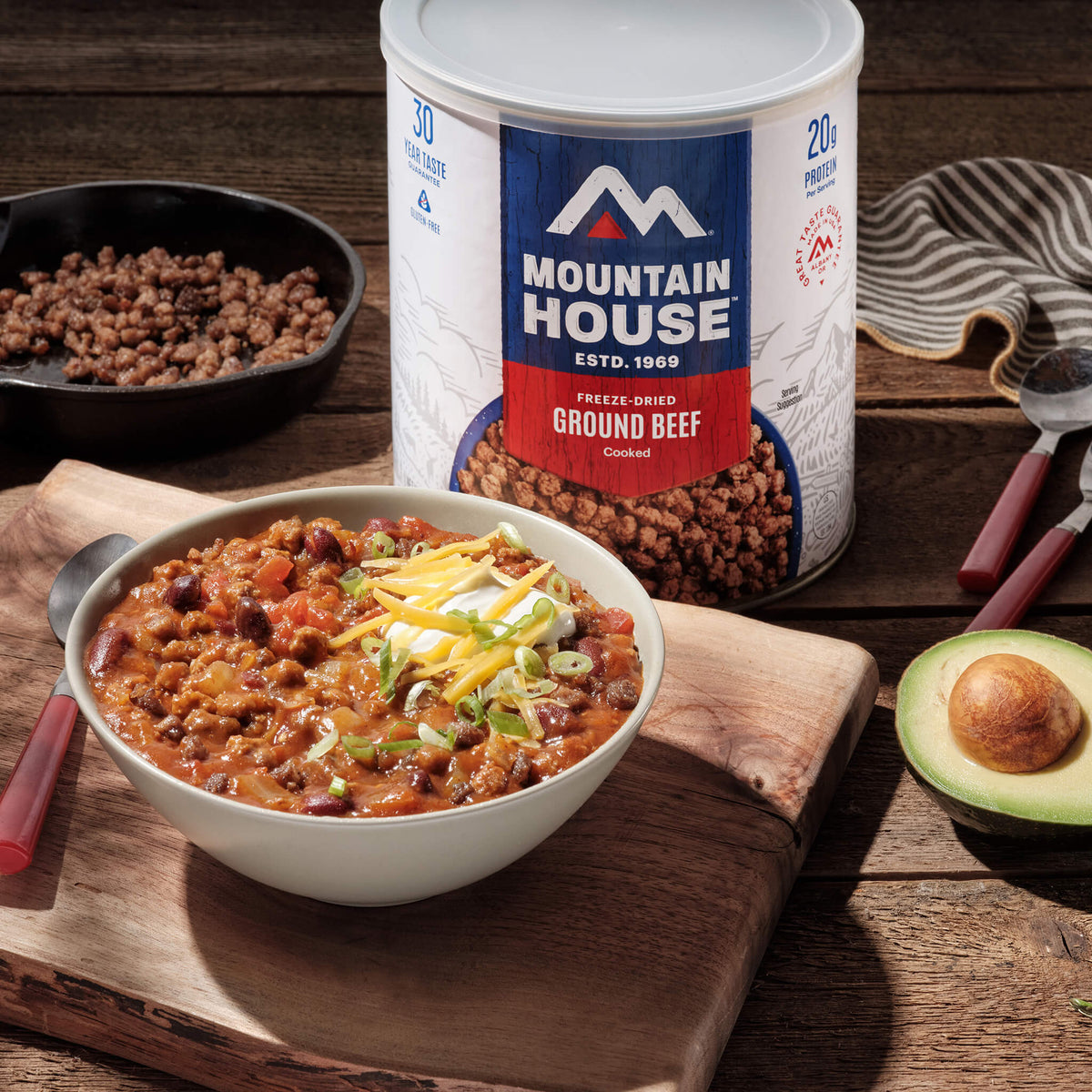 Bowl of chili with cheese and avocado next to a can of Mountain House freeze-dried ground beef.