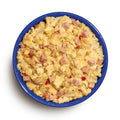 Blue bowl filled with scrambled eggs and ham, cheese, and peppers on a white background
