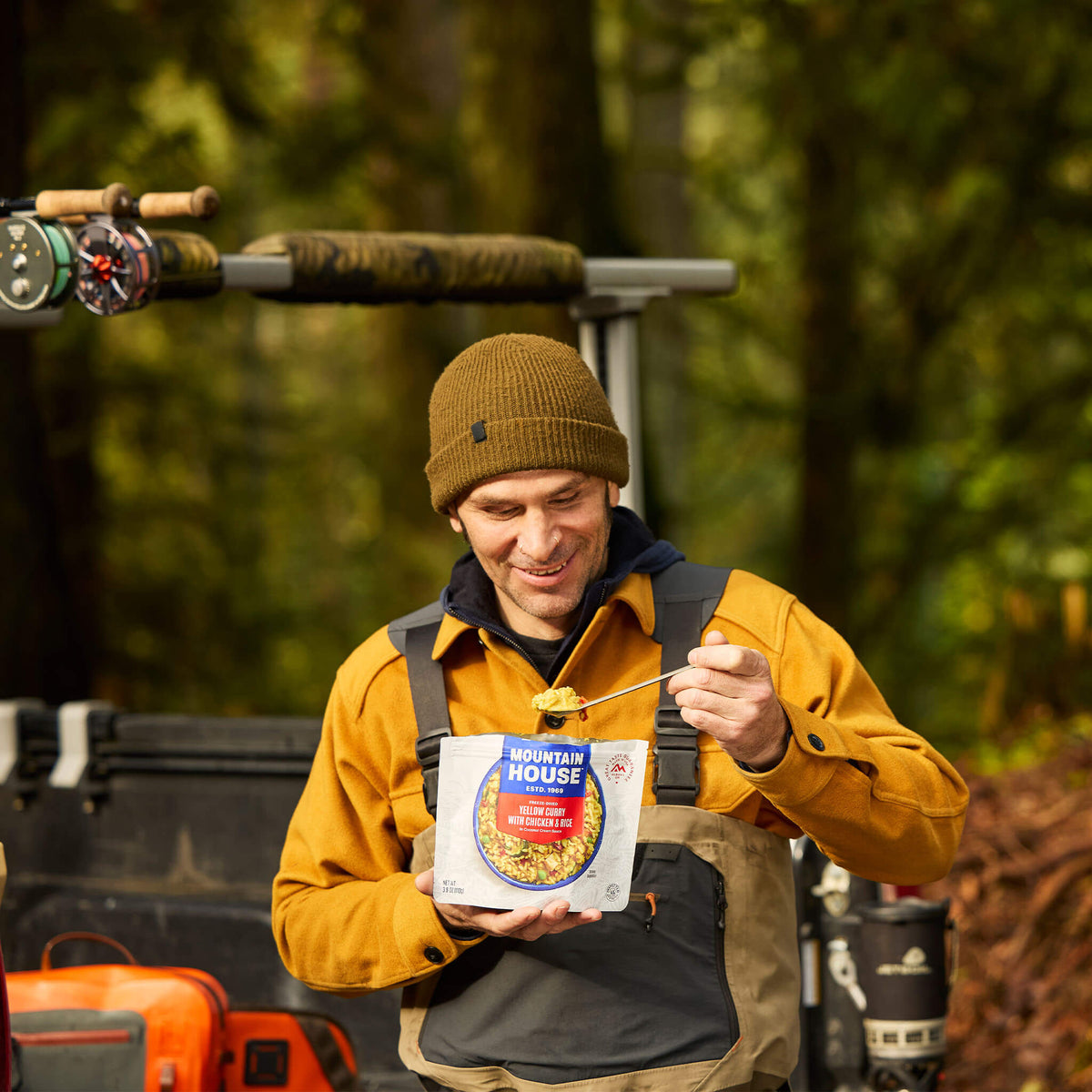 Person standing by truck in fishing waders scooping a spoonful of Mountain House Yellow Curry.
