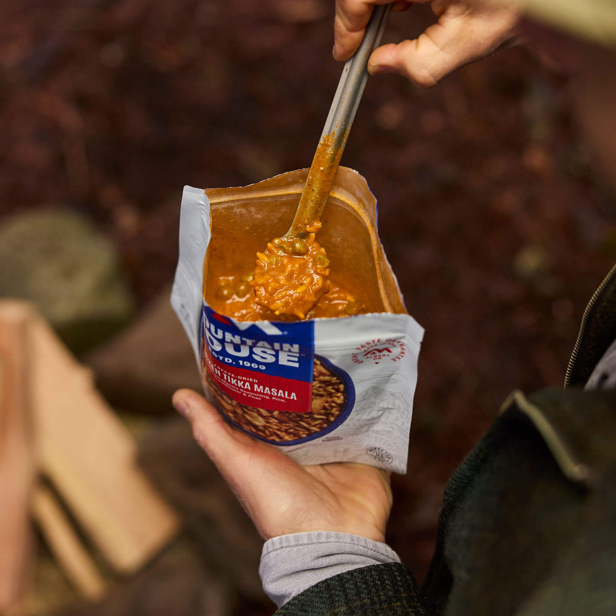 Close-up of person scooping out a spoonful of Mountain House Chicken Tikka Masala at a campground.