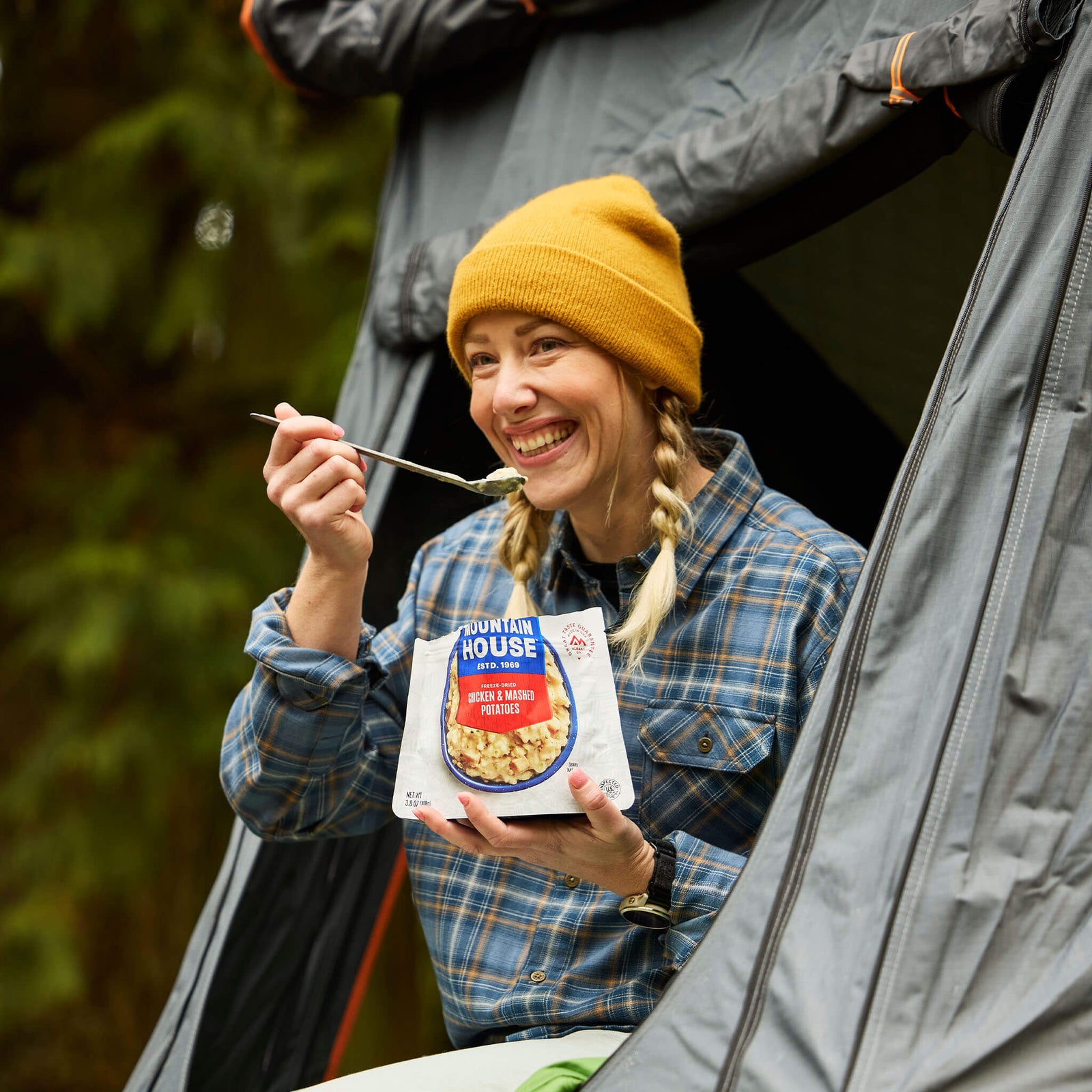 Gril sitting in roof tent taking a bite of Mountain House Chicken & Mashed Potatoes.