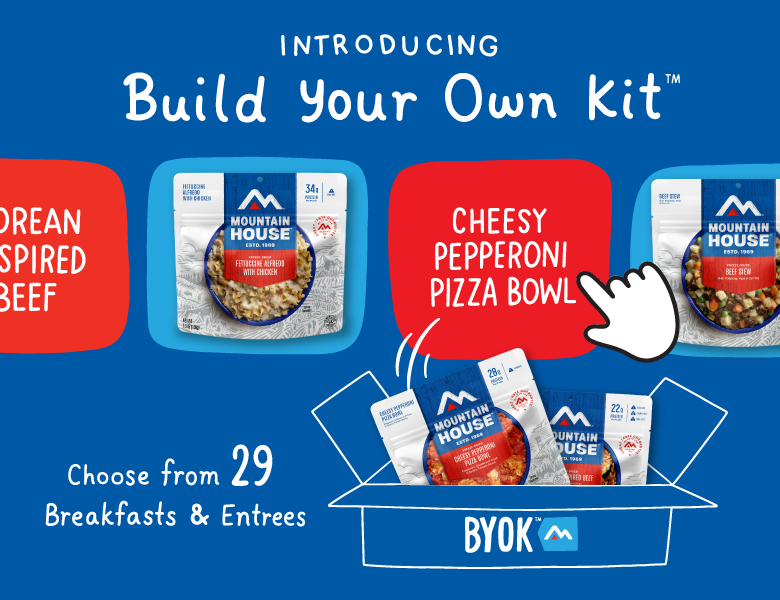 Blue background with Mountain House pouches being put into box. Text reads "Introducing Build Your Own Kit. Choose from 29 Breakfasts & Entrees."