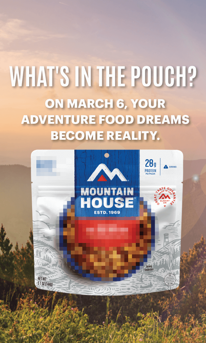 Picture of Mountain House pouch on a stump in the mountains. Text reads, "What's in the pouch? On March 6, your adventure food dreams become a reality."