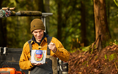 Person sitting on the tailgate eating a pouch of Mountain House Yellow Curry while on a fishing trip in the backcountry.