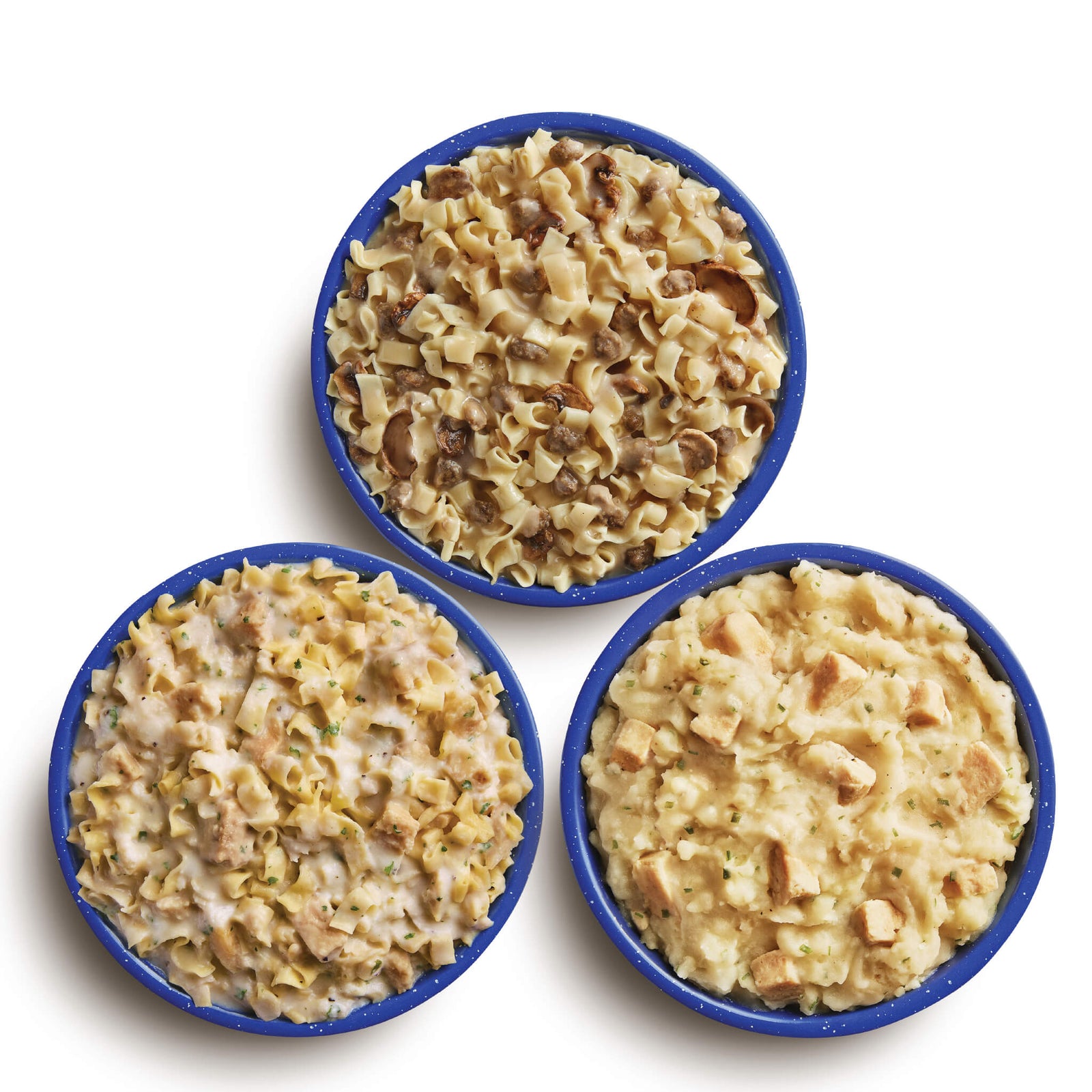 Three blue bowls filled with different Mountain House meals on a white background