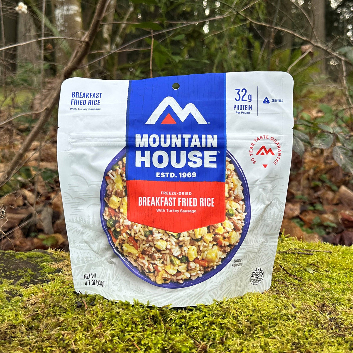 Mountain House Breakfast Fried Rice pouch resting on a moss-covered rock, with a forest in the background.